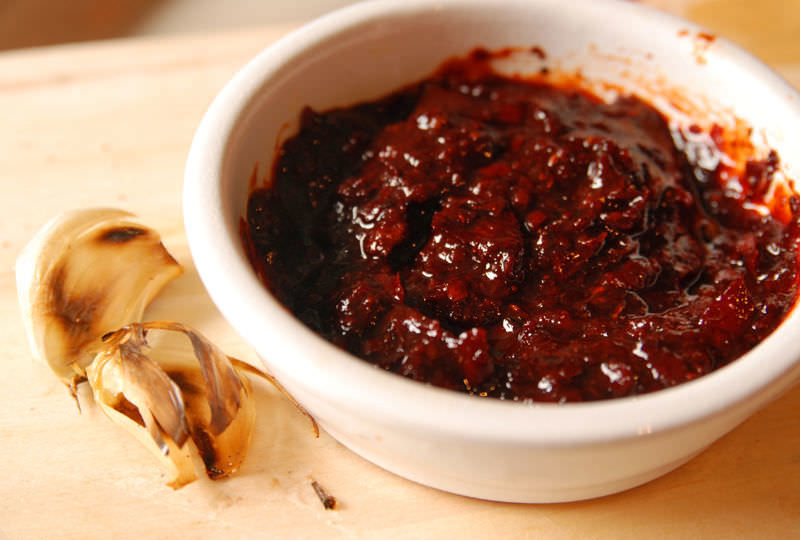 Epices de Cru Sweet And Sour Maple Syrup Salsa in a bowl with garlic next to it