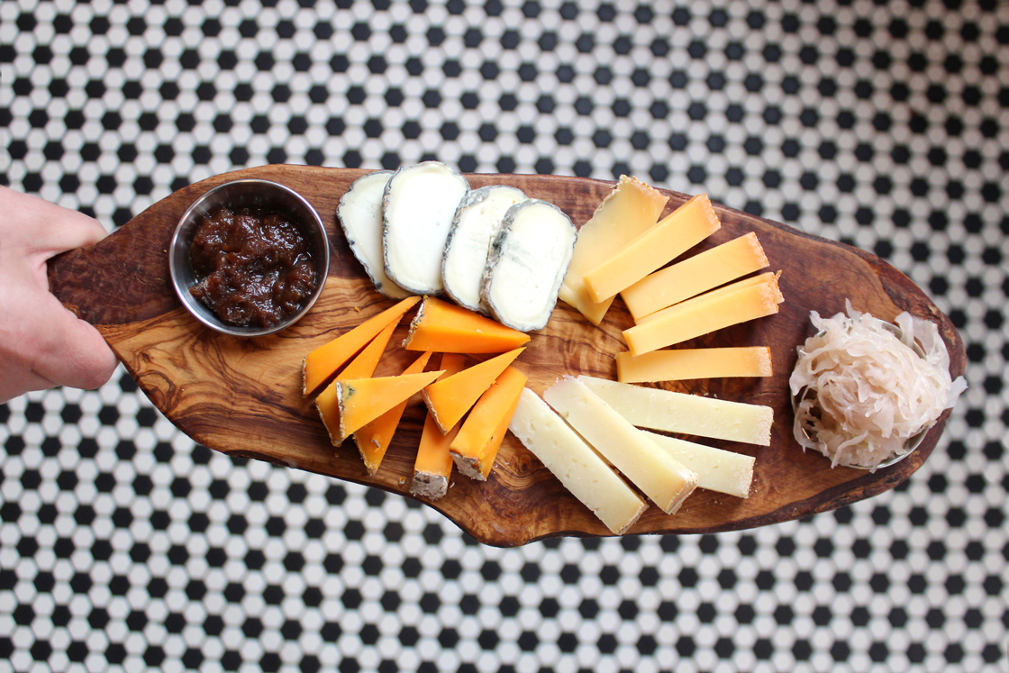 Zingerman's Deli staff holding a cheesemonger board with a variety of cheese and pairings, how to build cheese board