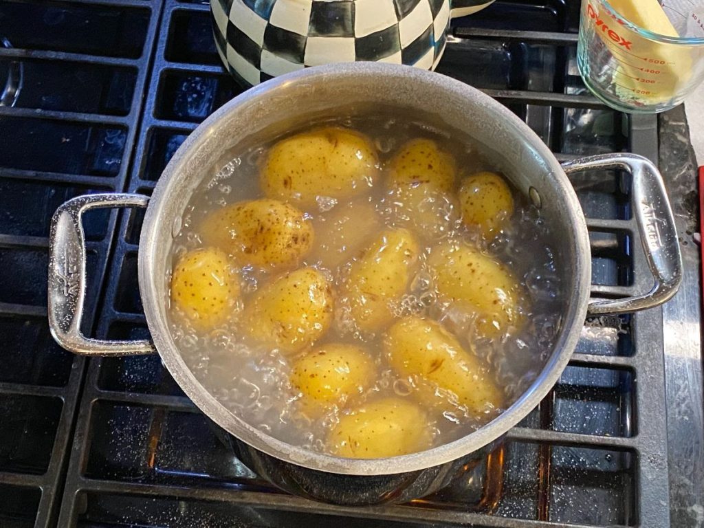 A photo of a pot of potatoes in water boiling on the stove.