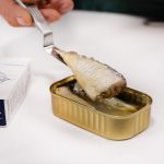 Sardines and Scrambled Eggs A sardine filet being lifted from its tin on a fork.