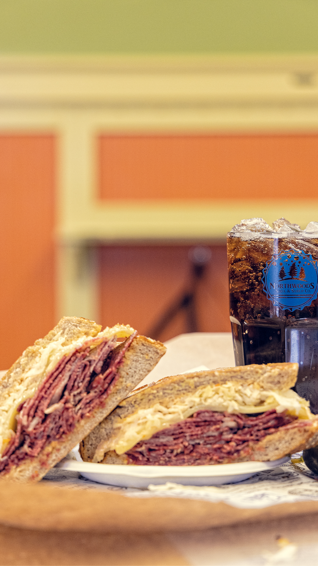 a photo of a reuben and a cup of Northwoods soda