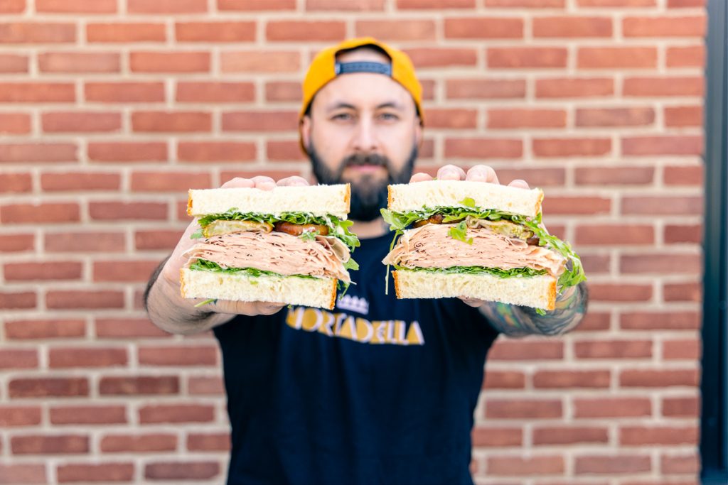 a photo of our sandwich line manager mike holding a mortadella sandwich