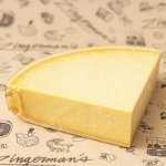 Dutch Gouda from De Graafstroom Dairy A quarter of a wheel of Dutch Gouda cheese on a sheet of Deli parchment paper.