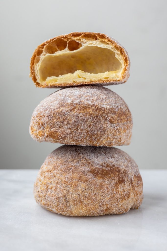 A photo of three lemon clouds stacked on top of each other on a marble surface, with the top lemon cloud cut in half to show the inside.