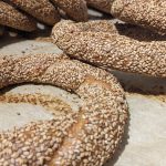 A photo of several Simit resting on a parchment-lined sheet tray.