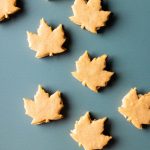 A top-down photo of several maple leaf sandwich cookies on a slate gray surface.