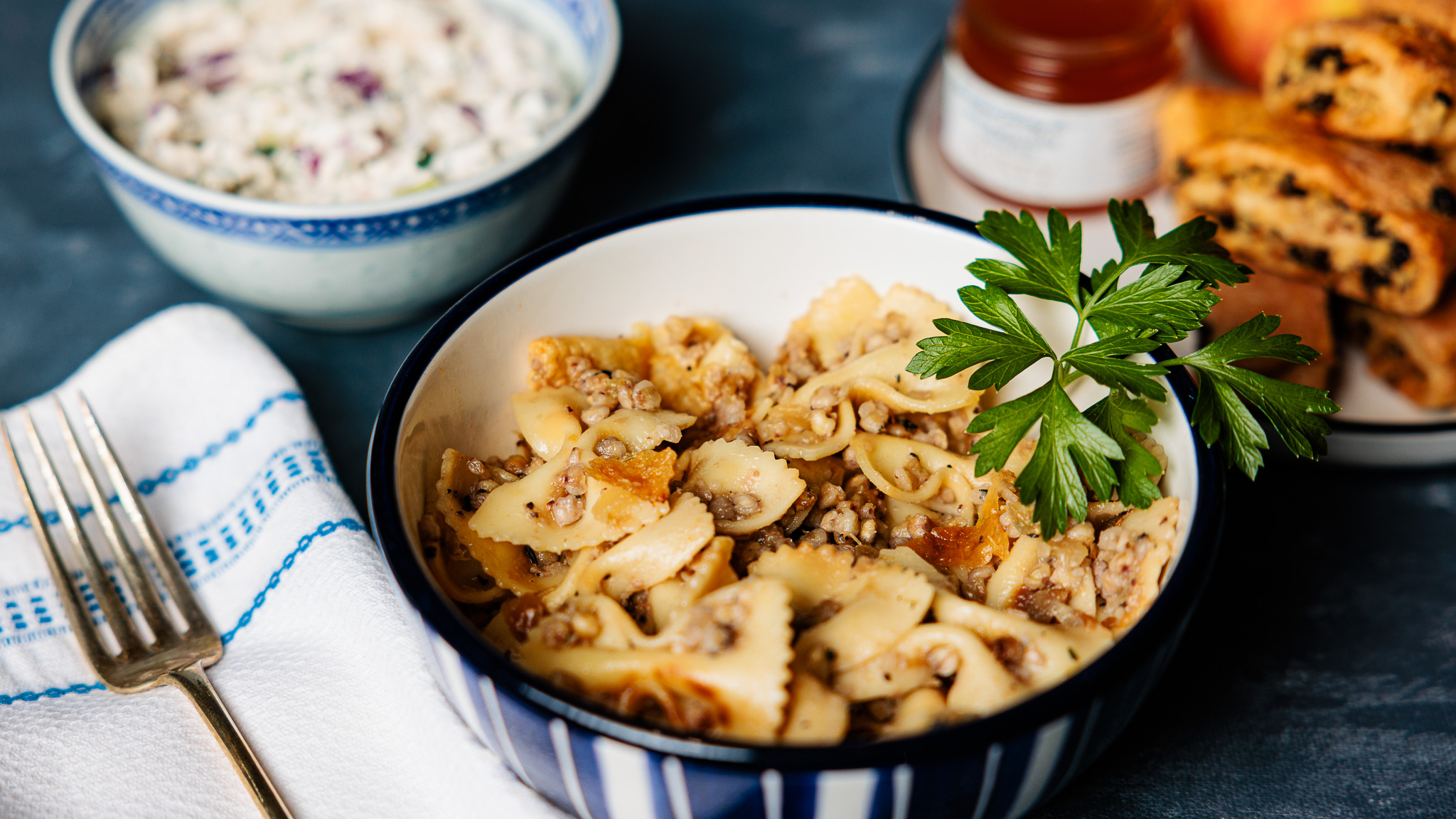 A photo of a bowl of Kasha Varnishkes topped with a sprig of parsley.