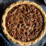 Pecan Pie Gets Even Perkier with Cultured Butter in the Crust A top-down photo of a Pecan Pie on a dark slate gray surface.