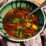 Rolando Beramendi’s Fresh Spring Vegetable Soup A photo of a ceramic bowl of Fresh Spring Vegetable Soup with a spoon resting in the bowl.