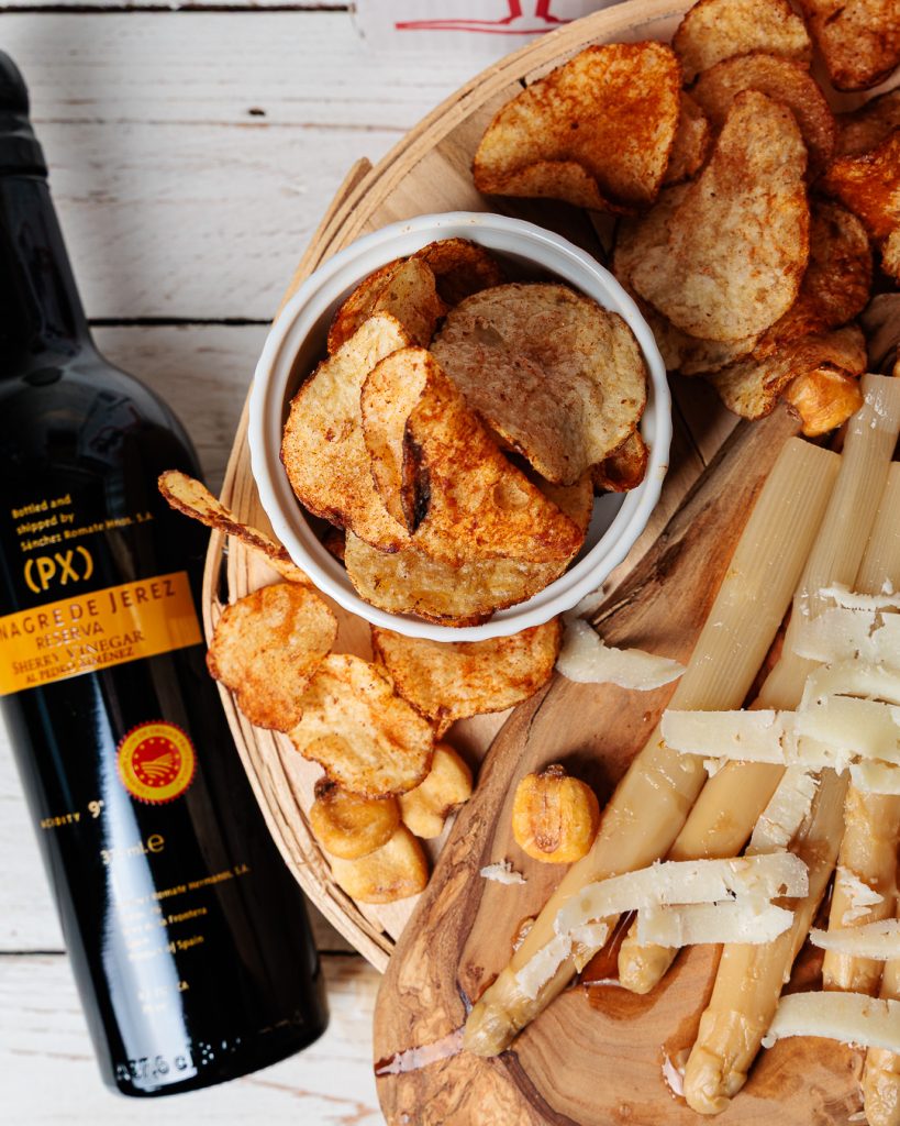 A top-down photo of a bottle of Sanchez Romate PX Vinegar next to a cheeseboard.