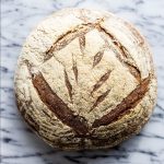 Two-Kilo Country Miche from the Bakehouse A top-down photo of a boule of Country Miche on a marble surface.