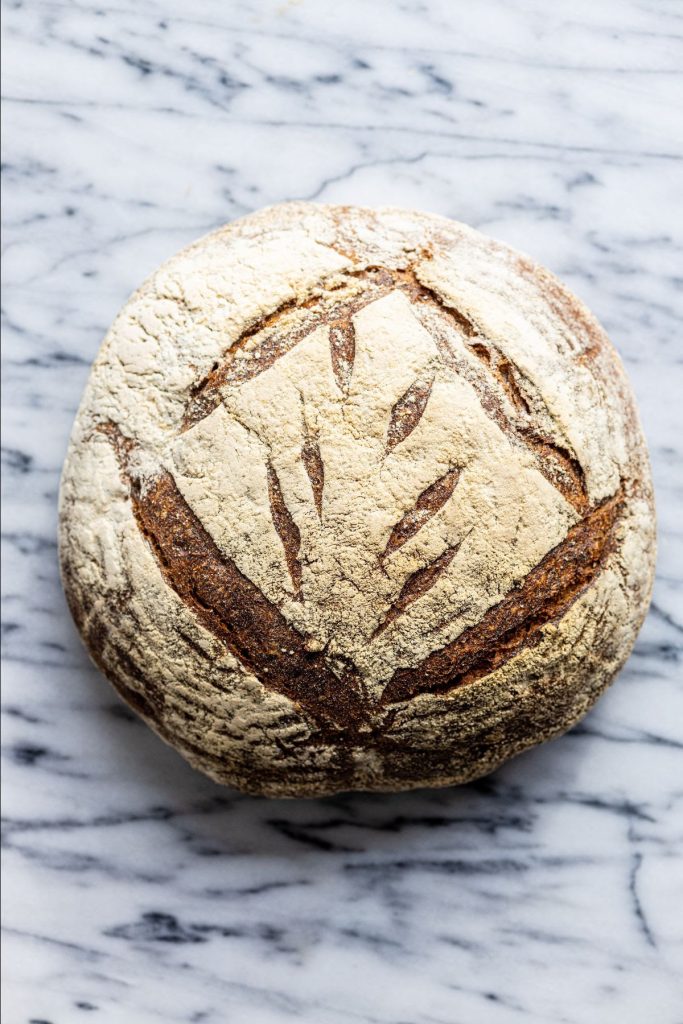 A top-down photo of a boule of Country Miche on a marble surface.