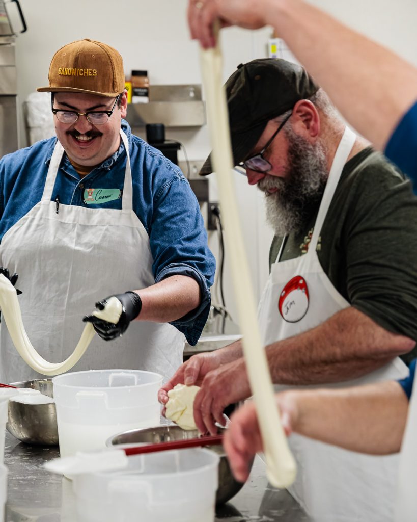 A photo of Connor stretching mozzarella with a class of students. 
