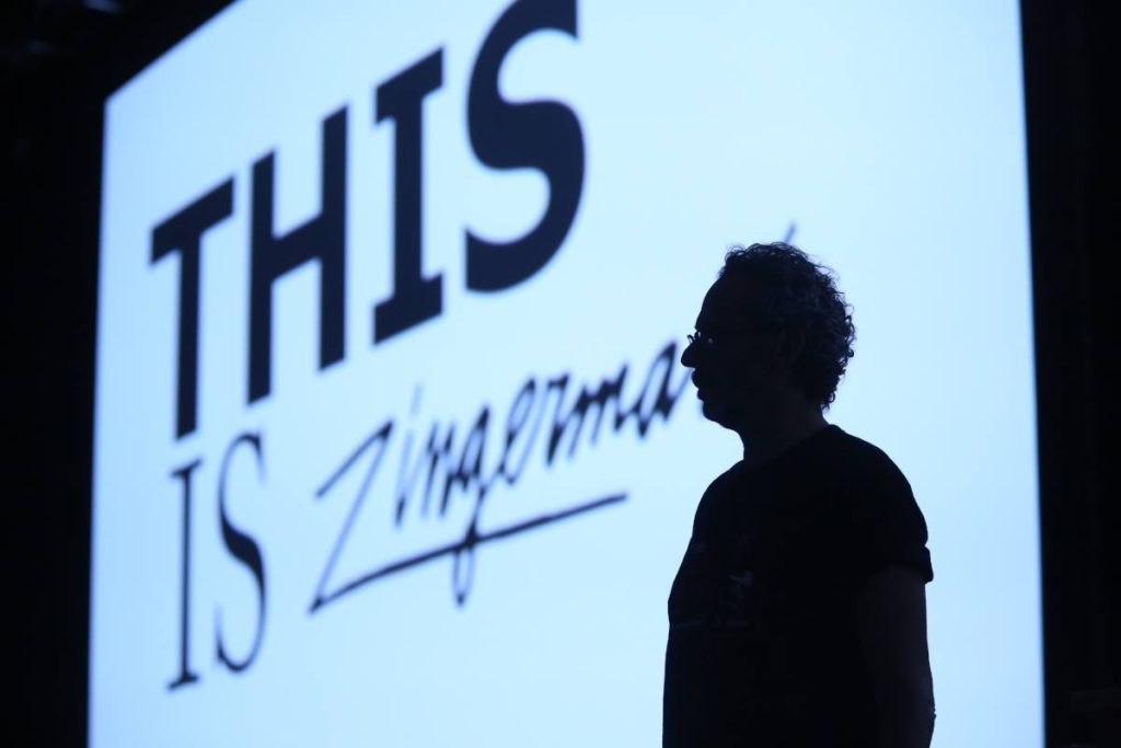 A photo of Ari's silhouette in front of a projector screen reading "This is Zingerman's."