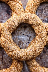 A top-down photo of five rings of Simit on a metal baking tray.