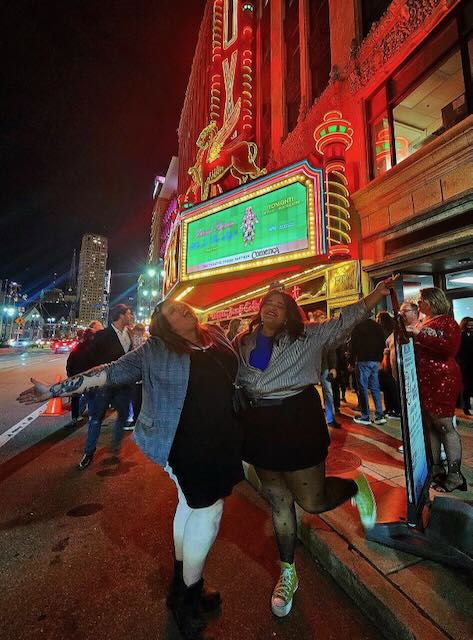A photo of Asha and a friend in front of a theater in Detroit.