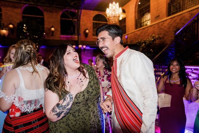 A photo of Asha laughing with a friend at his wedding reception.