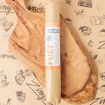 Fuet from Lowry Hill Provisions A top-down photo of a wrapped log of Fuet on a wooden serving board.