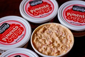 A photo of several containers of Zingerman's Pimento Cheese, one of which is opened to show the dip inside.